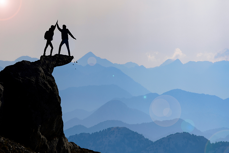 Zwei Bergsteiger auf dem Gipfel geben sich High-Five